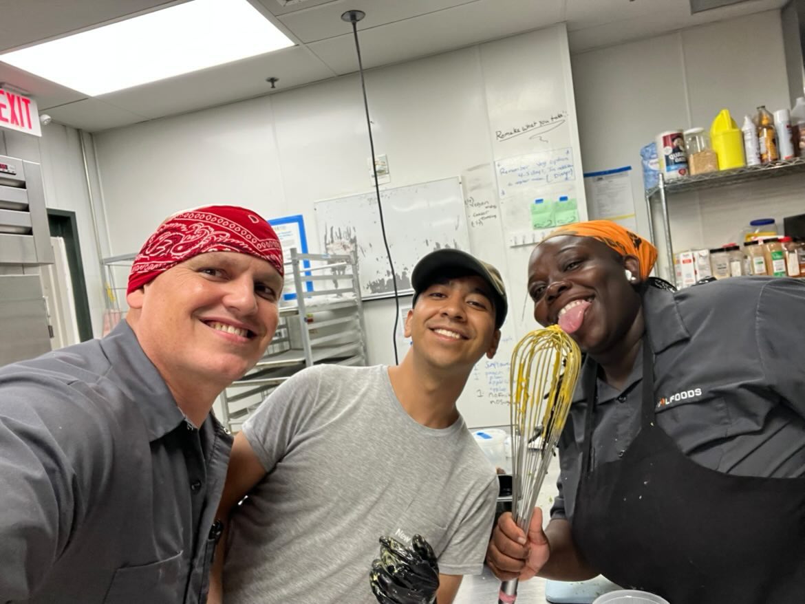 Kitchen team smiling with a whisk